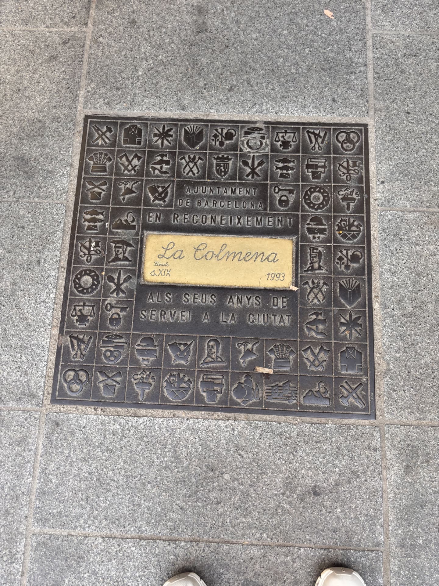 A bronze guild plaque set in the pavement of Barcelona's Gothic Quarter, reading La Colmena beneath the Ajuntament de Barcelona dedication and dated 1993.