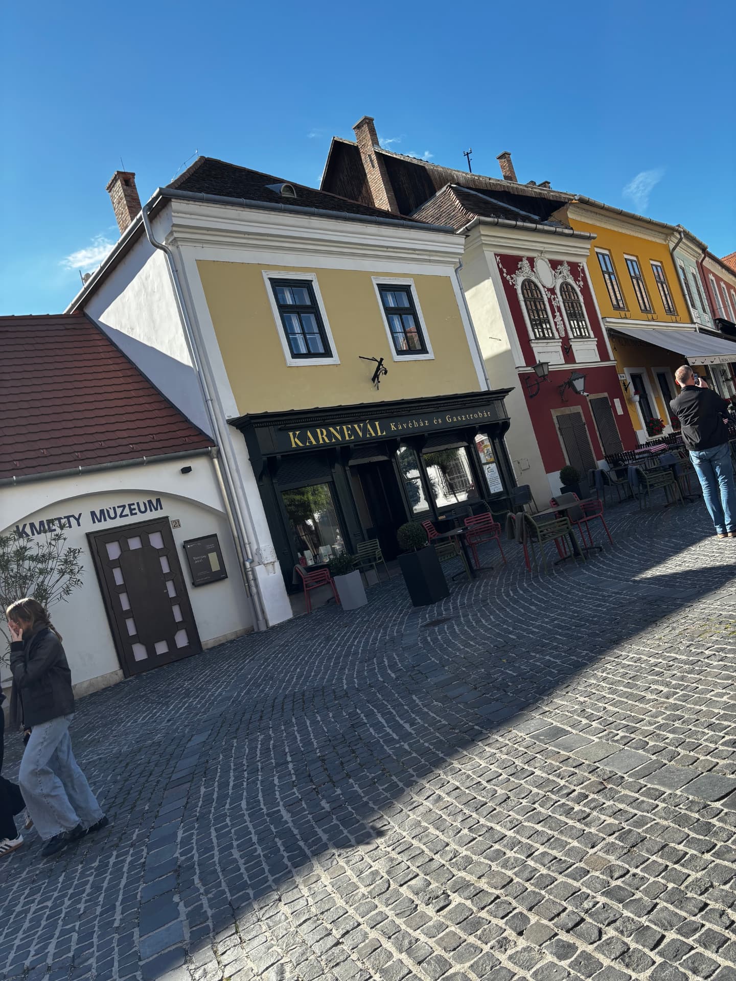 Colourful painted townhouses around a cobbled square in Szentendre, with the Kmetty Museum building and the Karneval cafe.